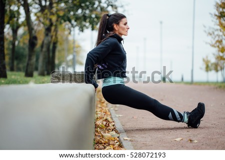Portrait of woman in sportswear, doing fitness push-ups exercise at fall park, outdoor. Healthy lifestyle, weight lossing and sporting theme concept shot. Triceps dips. Royalty-Free Stock Photo #528072193