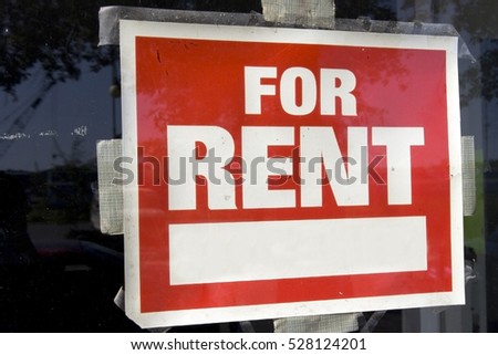 Red and white For Rent Sign taped to inside of window. Horizontal.