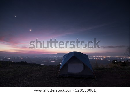 camping tent on mountain and sunset with moon,star and city town.Camping concept