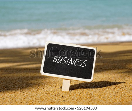 Selective focus of chalk board written with BUSINESS text. Wave and blue ocean background