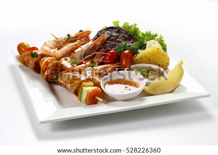 Skewered Chicken meat kebab Barbecue on wooden stick & Grilled Tiger Prawns & Beef Fillet Steak with Sauce & Lemon with Roasted Potato on White Square Plate on White Background. Platter Set, Side View