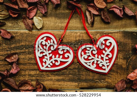 Beautiful wooden hearts with red dry petals around on a rustic wood