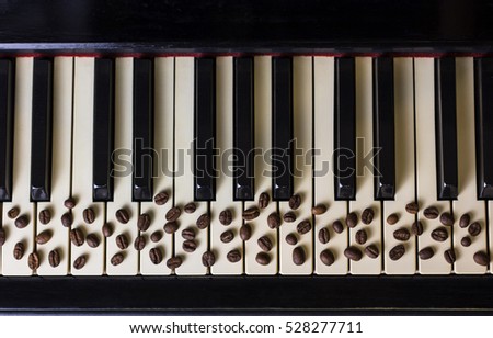 Coffee beans lying on the old piano keys close up