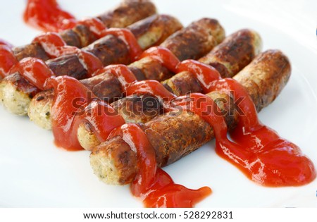 Grilled sausage  pour with Ketchup on white background (German name is Rostbratwurst.)
