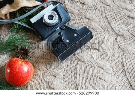 Old camera on the knitted background with apples and Christmas pine branches