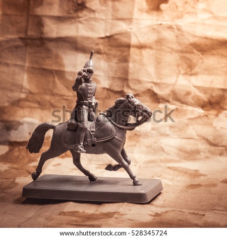 Figurine soldier on a horse on the background of old paper.