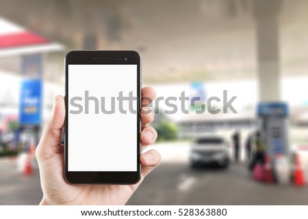 left hand using smartphone with blank screen on Abstract blur background of gas station