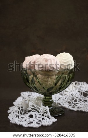 Zephyr (Russian Marshmallows). Sweet homemade treats in a glass green bowl . Soft focus. Dark brown background.