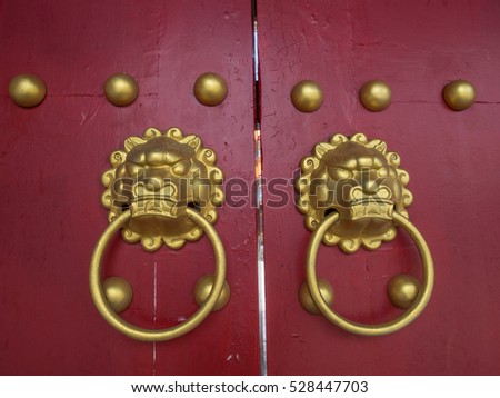 Golden door knocker  in a shape of a lion's head on a red wooden door