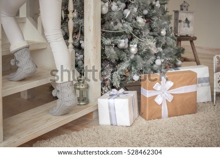 Beautiful girl puts presents under the christmas tree and goes upstairs/Christmas Gifts for Family