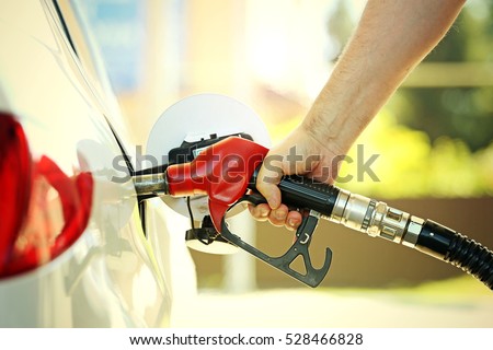 Hand refilling the car with fuel at the refuel station Royalty-Free Stock Photo #528466828