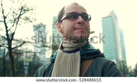 Cheerful programmer wearing black rim glasses walks on city business street