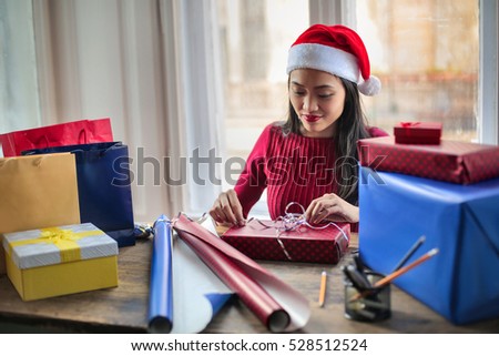 Young girl wearing a Christmas hat is packing Christmas presents