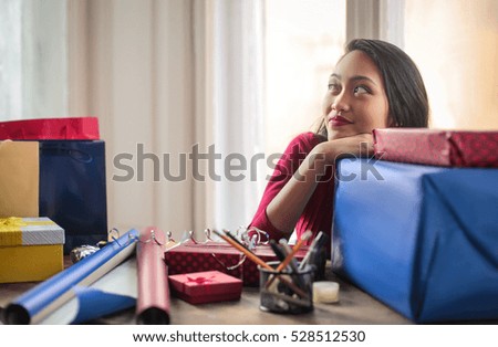 Beautiful girl thinking while she is packing some presents
