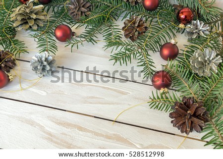Christmas decoration with branches from fir cones and toys on white wooden background