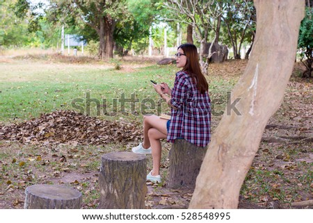 Women are playing mobile phone. In the park