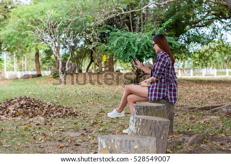Women are playing mobile phone. In the park