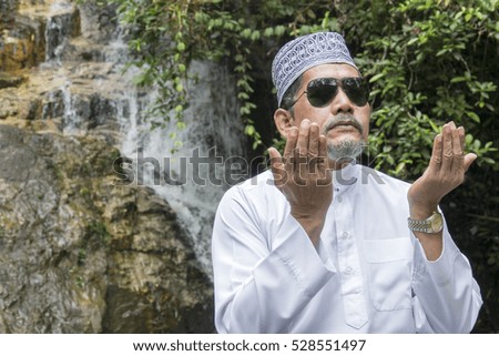 Adult muslim praying at waterfall.