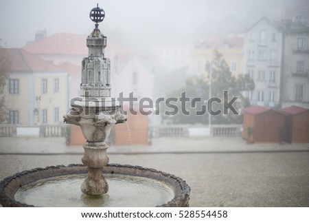 Landscape on the source of the entrance of the National Palace of Sintra and the village of sintra on a foggy day Royalty-Free Stock Photo #528554458