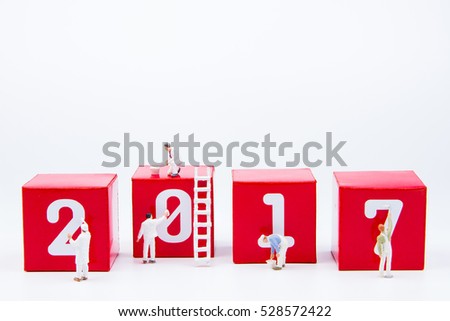 Tiny toy painter are painted white color 2017 number on red paper box cubes on isolated white background with copy space.Year of the Cock.Happy new year 2017 concept background.