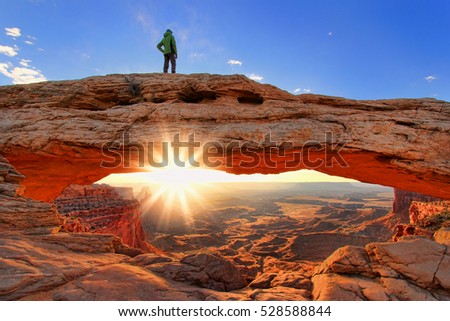 Silhouetted person standing on top of Mesa Arch, Canyonlands National Park, Utah Royalty-Free Stock Photo #528588844