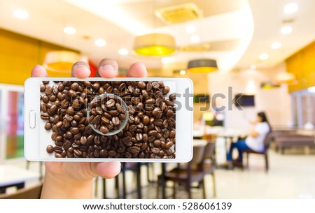 Man use mobile, coffee bean on screen and blur image of coffee shop as background.