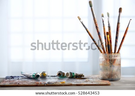 Paint brushes with a palette on a light background. Royalty-Free Stock Photo #528643453