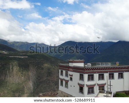 Tibetan Traditional White house with ornaments on the edge of the mountain in Fei lai, Yunnan, China, facing beautiful blue mountains in the clouds.