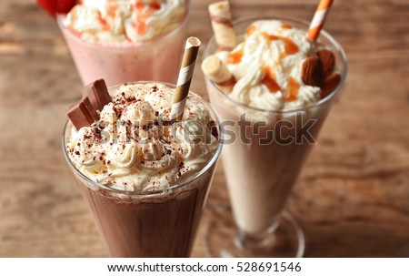 Delicious milkshakes on wooden background Royalty-Free Stock Photo #528691546