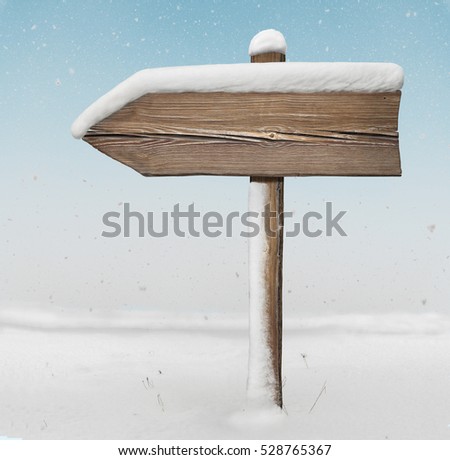 Wooden direction sign with less snow on it and with snow on background