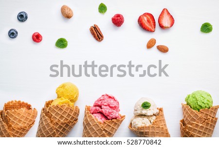 Colorful  ice cream with cones and various fruits raspberry ,blueberry ,strawberry ,almonds and peppermint leaves setup on white background . Summer and Sweet menu concept flat lay and copy space .