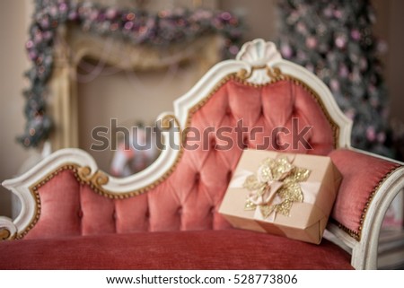 On the vintage sofa a Christmas gift, decorated with gold leaves/Christmas Background out of Focus