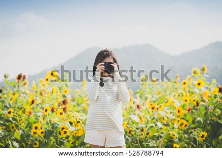 Beautiful Asian girl taking pictures on the sunflowers field