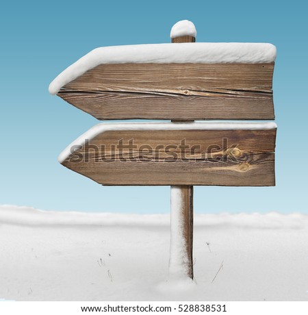 Wooden direction sign with less snow on it and with sky on background. two arrows in one direction