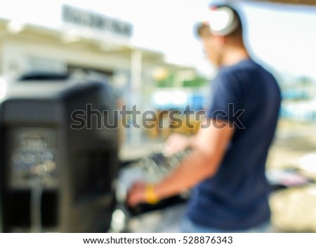 Blurred disc jockey playing music outdoor in summer time dj set - Defocused image - Blurry background - Party concept - Warm filter