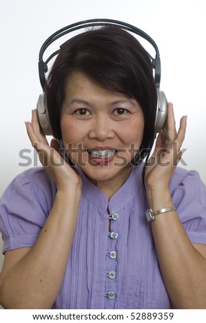 Middle aged Asian woman listening to music on headphones