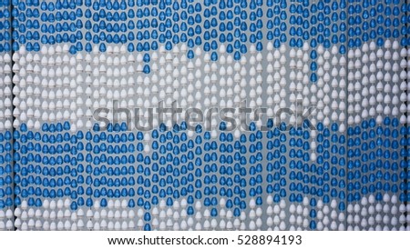 Full frame of a plastic pearl door blind and curtain on a white barkground in blue and white pattern.