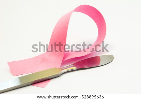 Concept surgery treatment or plastic of breast. Pink ribbon as symbol of breast pathology, lies next to surgical scalpel. Photo for surgery operations such as reconstruction, reduction, uplift ets