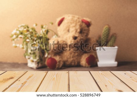 Wooden board empty table in front of blurred background. Perspective brown wood over teddy bear, chamomile flower and cactus for mock up  display or montage your products, vintage and warm tone. 