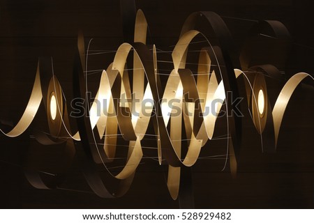 Double exposure photo of lighting fixture with spiral / ribbon structure in mysterious backlight. Realistic though unreal modern architecture / interior detail Royalty-Free Stock Photo #528929482