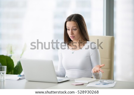 Young businesswoman at the modern office desk with laptop puzzled by a private photo posted, result of election, salary, world currency exchange rates, can not believe her eyes