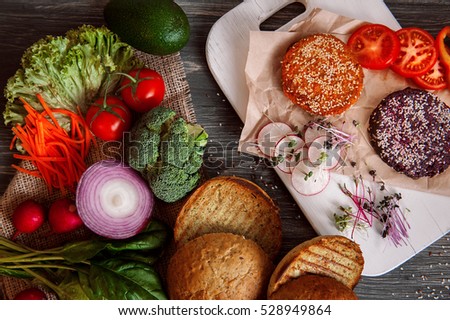 Vegetables and bread rolls for a vegetarian burger on a black wooden background. veganburger