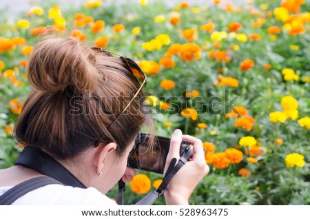 Female photograph with camera taking a picture of Marigold flower