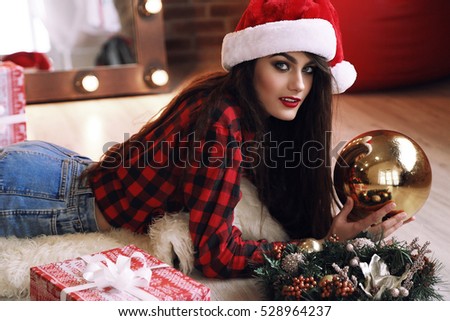fashion studio photo of beautiful charming woman with dark hair in warm cozy winter clothes posing near Christmas tree with presents and New Year deco