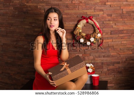 Woman in red dress opening Christmas present