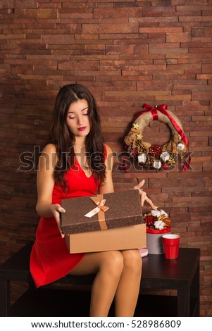 Woman in red dress opening Christmas present