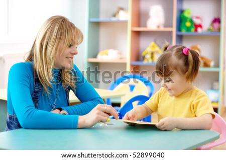 Teacher play with cute child in preschool