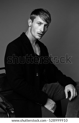 handsome young man in black jacket posing in studio, black and white photo