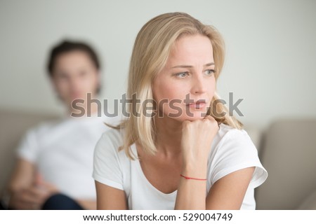 Serious sad woman thinking over a problem, man sitting aside, end of long-term relations, an alcoholic, drug addicted partner, poor conflict management skill, ongoing disagreements with adult son Royalty-Free Stock Photo #529004749