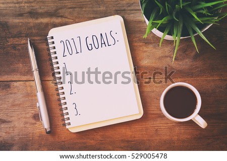Top view 2017 goals list with notebook, cup of coffee on wooden desk Royalty-Free Stock Photo #529005478